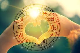 Heart-shaped hands with a zodiac wheel and sunlight, symbolizing astrological compatibility.