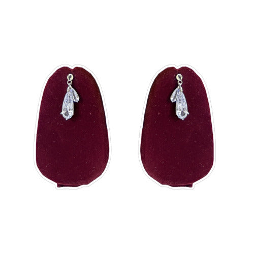 The Rosavelle Drop Silver Earrings on burgundy display.